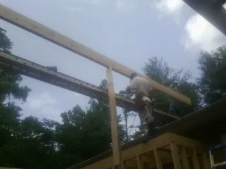 Carpenter setting a ridge beam over a new addition frame — Ice Dam Removal by Roofing Brothers in Blanchard