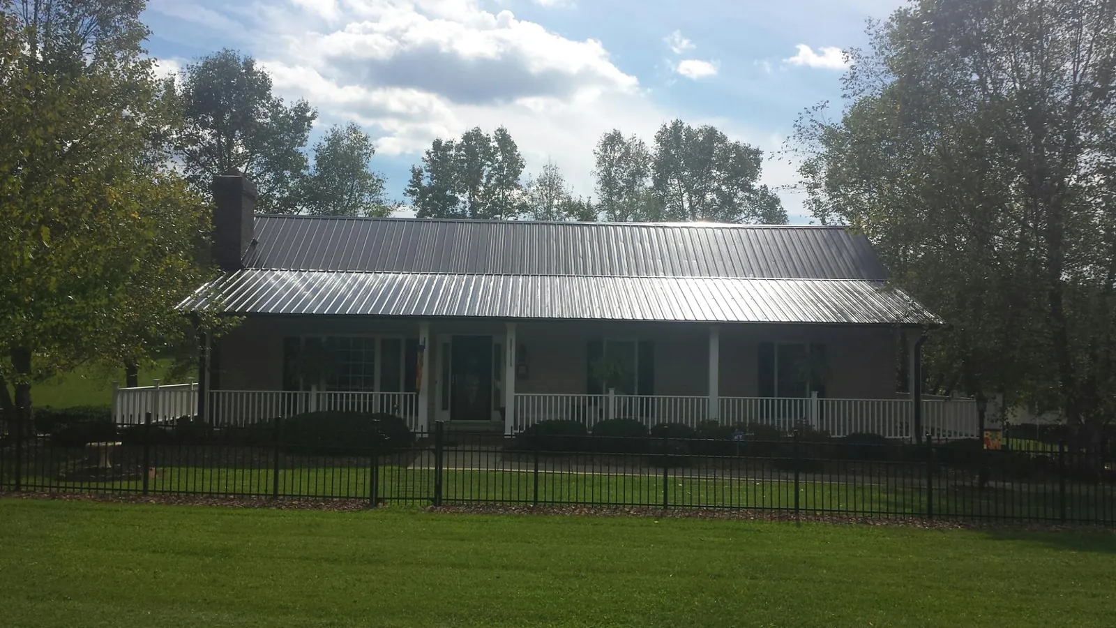 Gray metal roof on a brick ranch with a full width front porch — Gutter Guard Installation work by our crew in Blanchard